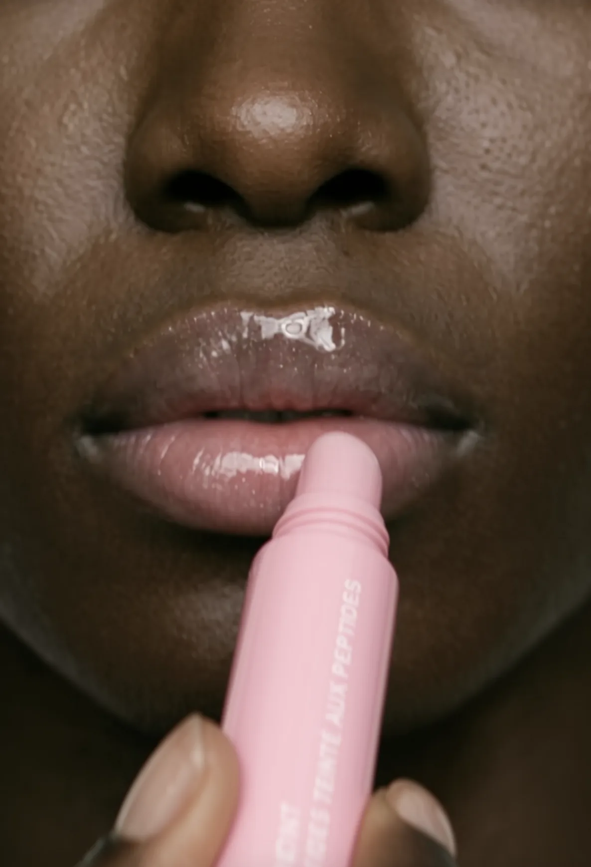 Close-up of lips with a pink lip balm tube