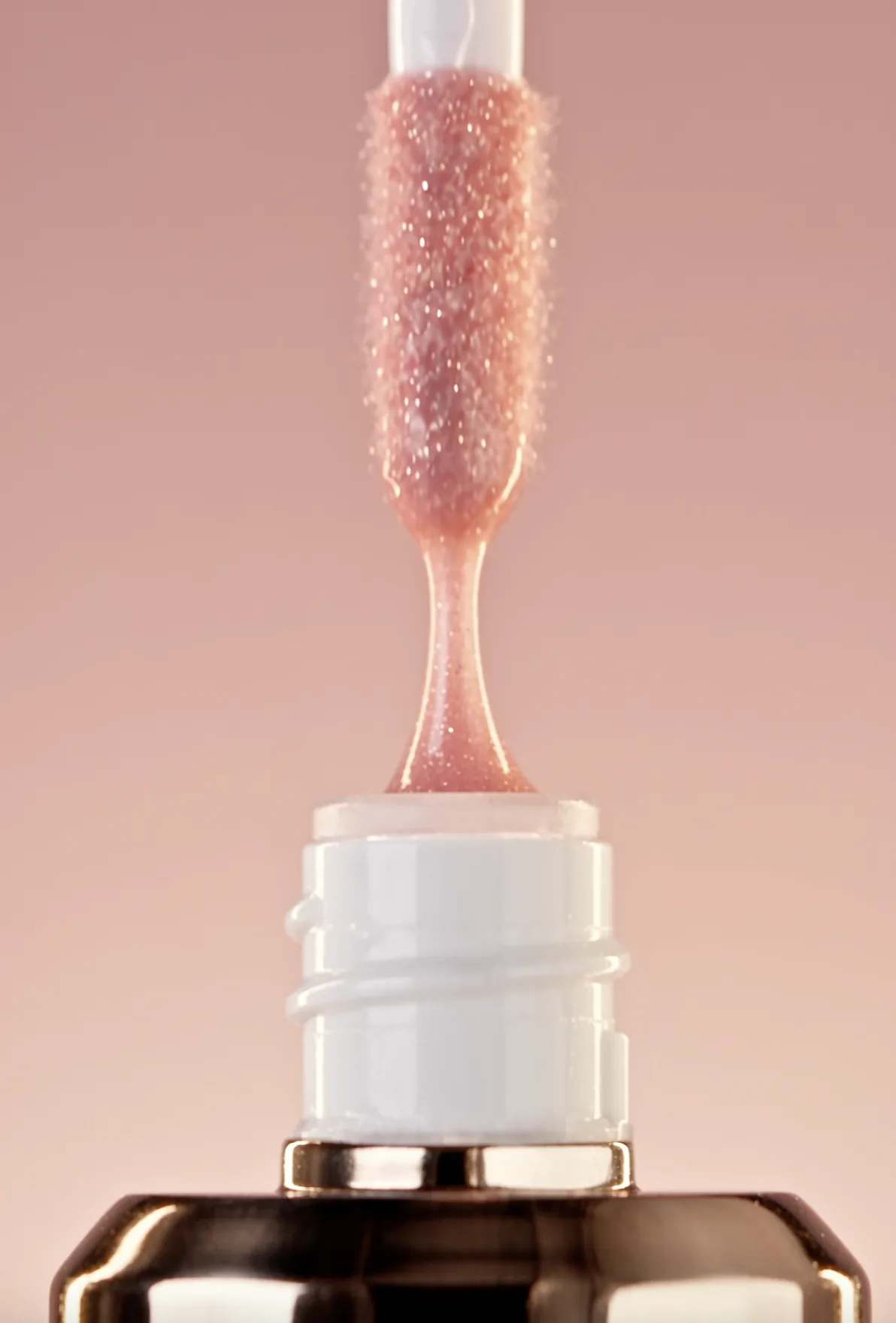 Pink gloss dripping from an applicator