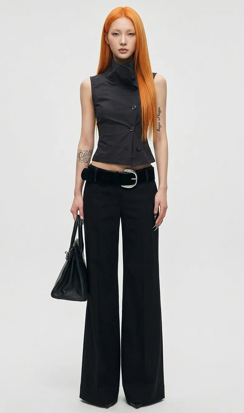 Model with long orange hair in a black vest and wide trousers