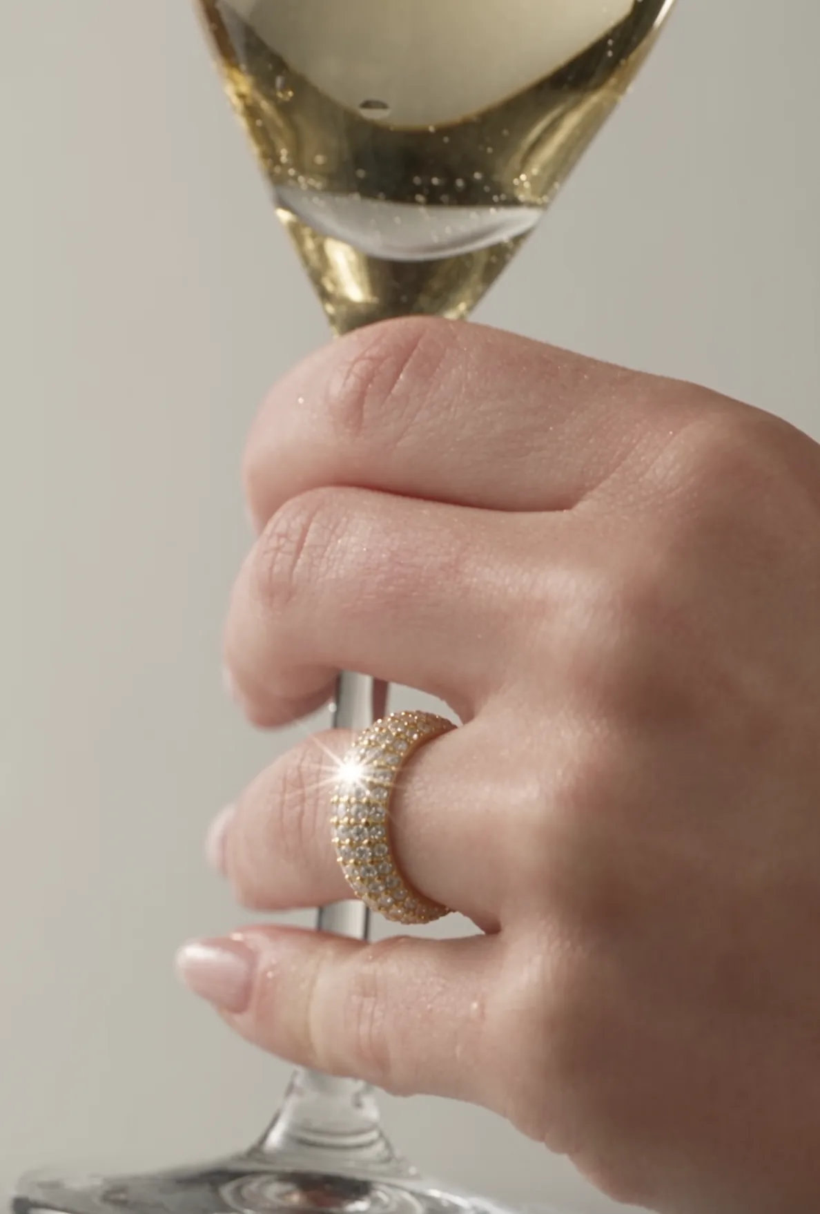 Hand wearing a diamond ring holding a champagne glass